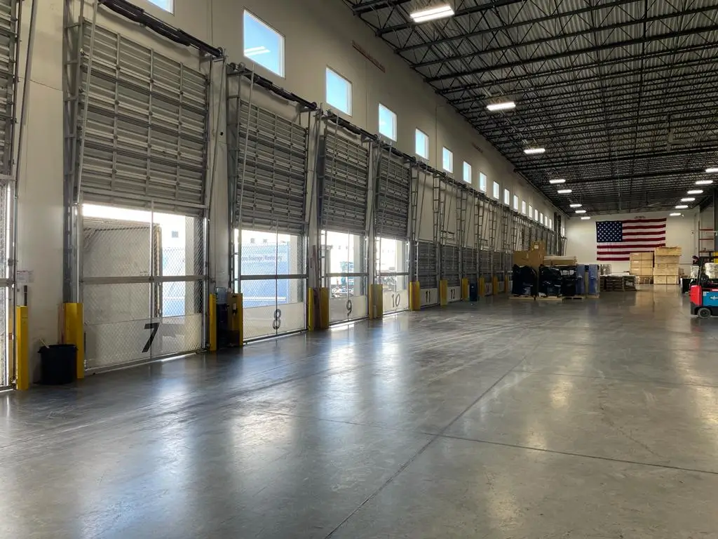 Interior of Draco Freight Logistics’ warehouse showing multiple loading docks, forklifts, and shipping bays prepared for efficient cargo handling and distribution.