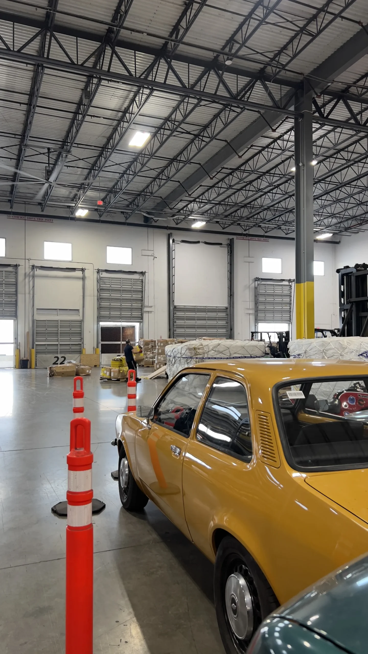 A classic vehicle positioned inside the Draco Freight Logistics warehouse, with automotive cargo and pallets being handled in the background as part of vehicle logistics operations.