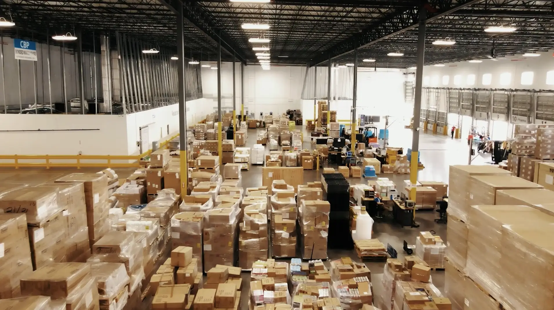 A wide-angle view of Draco Freight Logistics’ Miami warehouse showing organized pallets, high dock doors, forklifts, and active freight handling operations in a large, modern logistics facility.