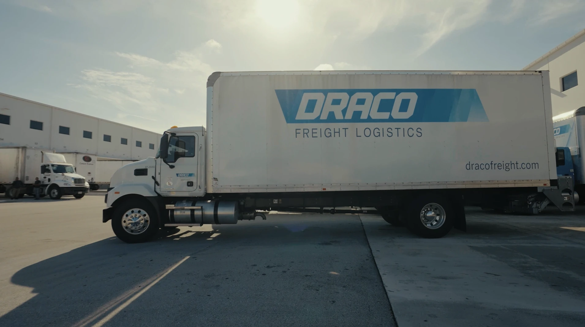 Draco Freight Logistics box truck positioned outside the warehouse under sunlight, ready for local and regional freight deliveries.