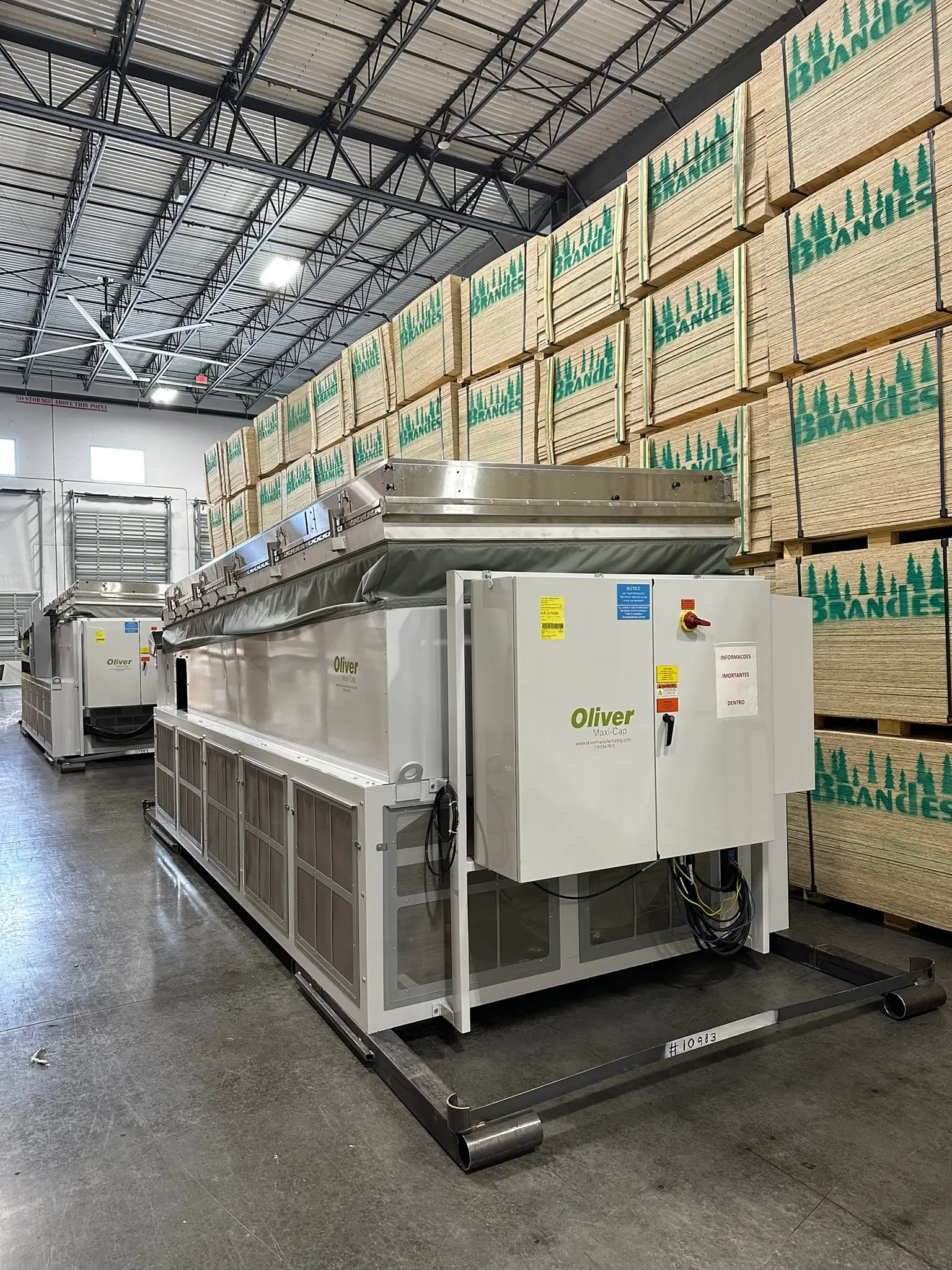 Oversized industrial machinery stored inside a warehouse alongside stacked wood pallets, showcasing Draco Freight Logistics’ capability to handle heavy and specialized cargo.