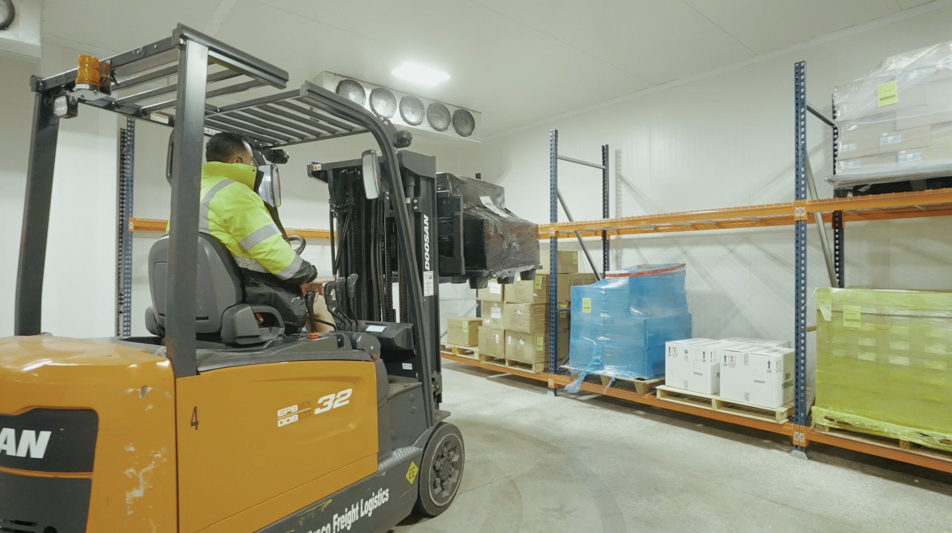 Warehouse worker operating an electric forklift to move pharmaceutical cargo inside Draco Freight’s temperature-controlled storage facility.